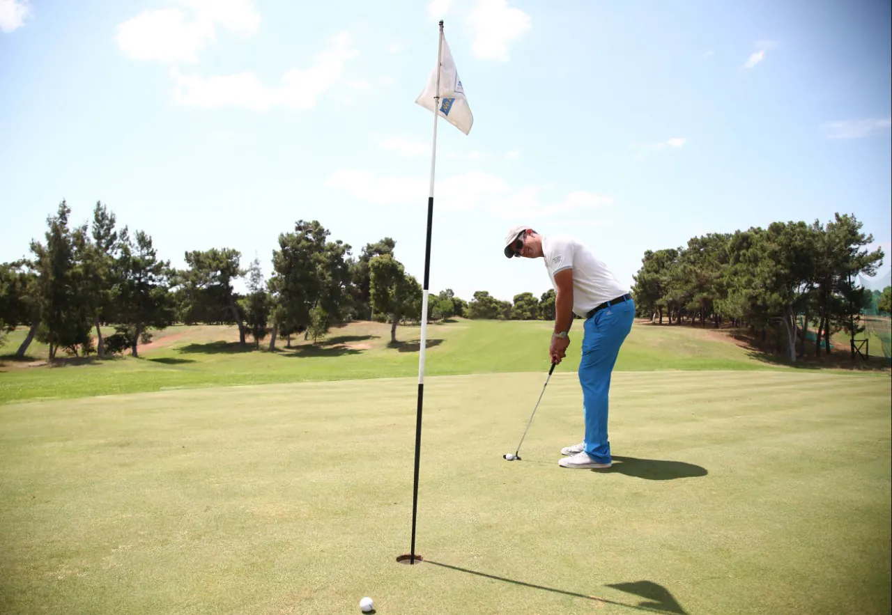 A golfer putting beside the flag on the green